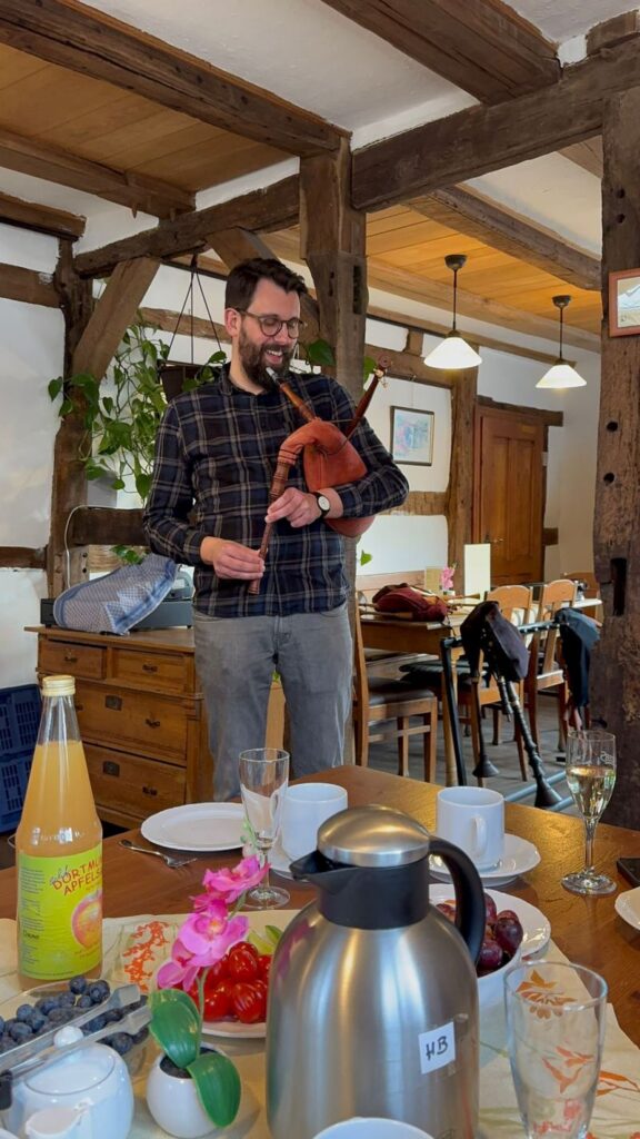 Teilnehmer eines Dudelsack-Workshops mit Instrument in einem Fachwerkraum