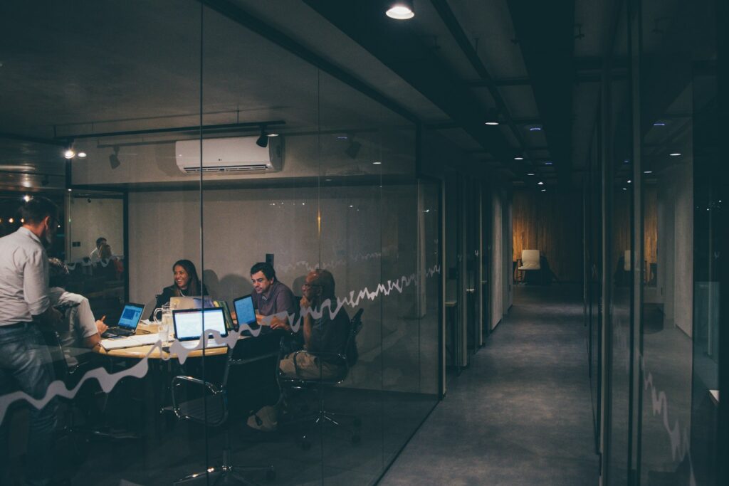 Kleines Team sitzt gemeinsam am Tisch und bespricht Arbeitsablaeufe