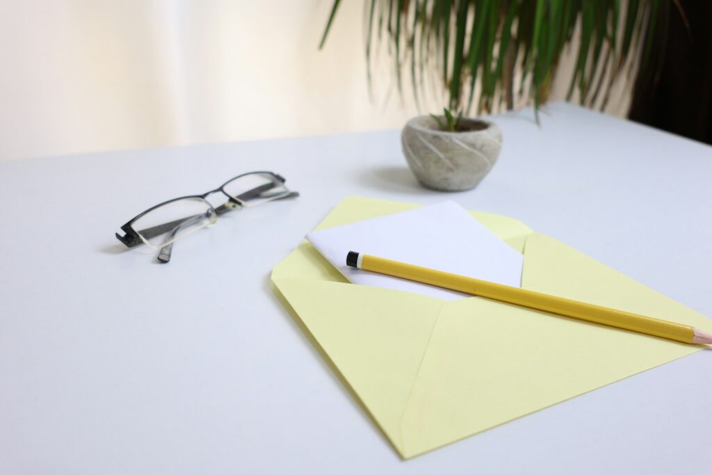 Gelber Umschlag mit Brief, Bleistift und Brille auf einem Schreibtisch
